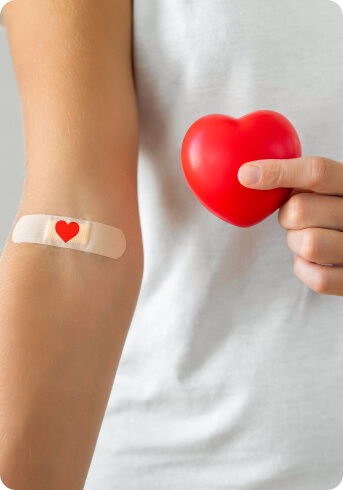 A szívecskés sebtapasszal ellátott plazmaadományozó egy jelképes szívet kezében tartva jelzi jócselekedeté